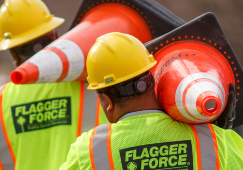 A group of construction workers wearing yellow and orange vests.