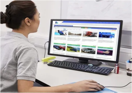 A woman sitting at her computer desk looking at the screen.