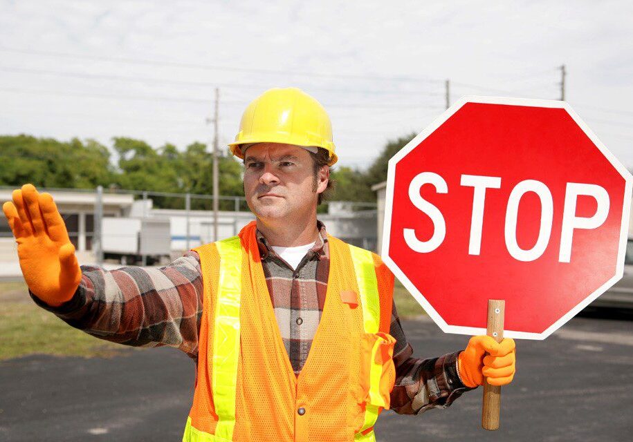 A man holding up a stop sign on the side of a road.